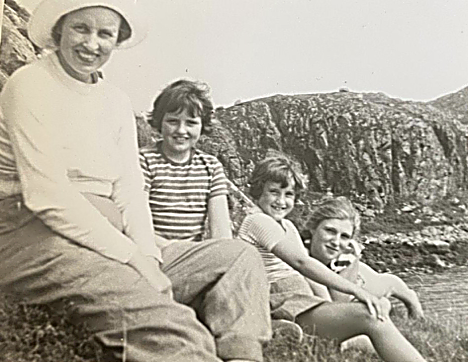 A woman and children sitting on a hillside watching sheepdog trials