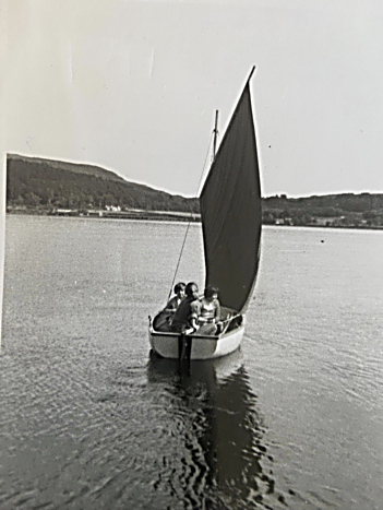 A small sailing dinghy with a red standing lug on Loch Ewe