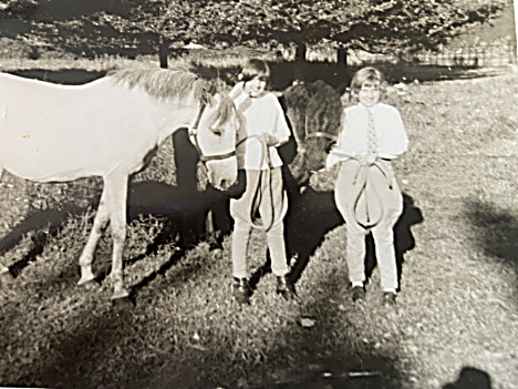 Two children standing in a field with Secret, the grey mare